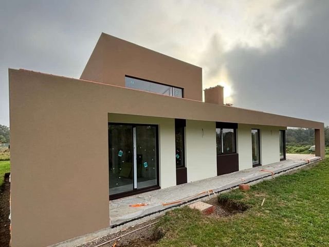 Vivienda moderna de una planta con fachada color arena y grandes ventanales