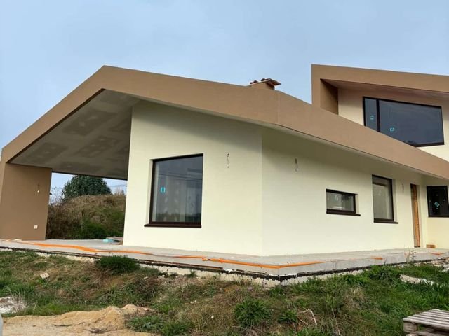 Vivienda con voladizo y fachada revocada color crema