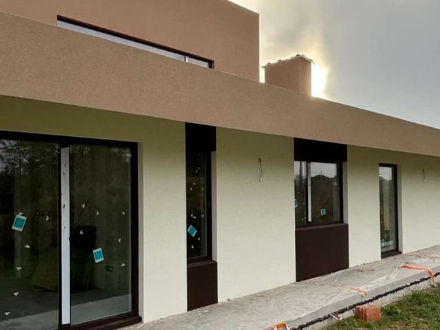 Fachada con ventanales correderos y carpintería oscura