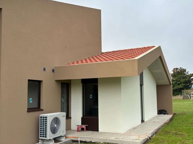 Lateral de la vivienda con cubierta de teja y máquina de aire acondicionado
