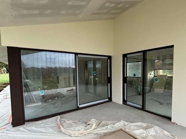 Salón con grandes ventanales correderos y techo de placas de pladur